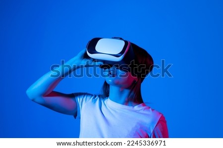 Young woman in virtual reality VR glasses playing a video games.