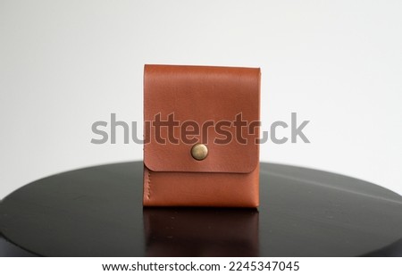 Close up orange men's business leather card holder on a black chair with a white background. Men's accessories.