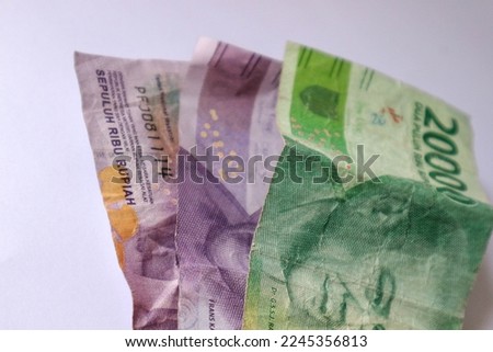 Isolated white photo of three rupiah banknotes. This money consisted of two ten thousand bills and one twenty thousand bill.
