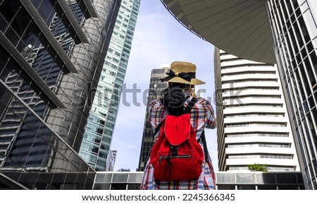 Backpack tourist woman taking picture at group of tall buildings in Singapore