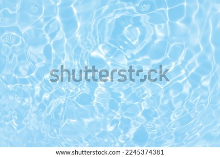 Defocus blurred transparent blue colored clear calm water surface texture with splashes and bubbles. Trendy abstract nature background. Water waves in sunlight with caustics. Blue water shinning  Royalty-Free Stock Photo #2245374381
