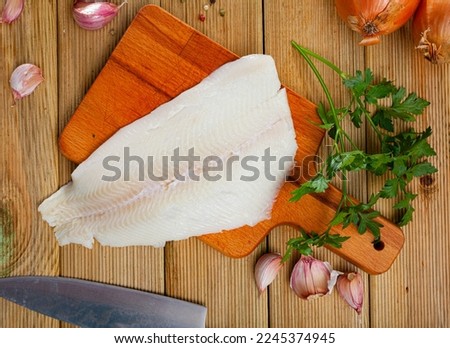 Image of fillet of raw halibut fish before cooking on wooden background with garlic