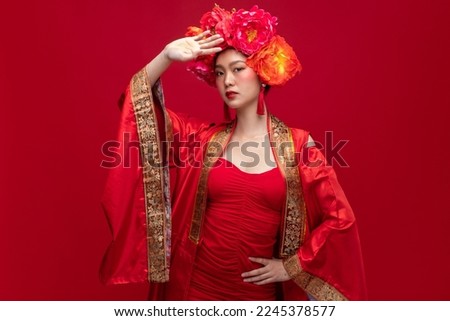 Portrait of young asian woman wearing fashion modern qipao cheongsam dress smile and flower on head on red background for Chinese new year festival