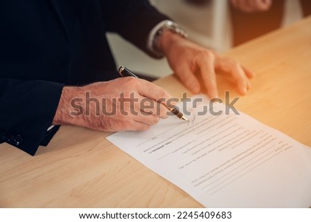 Close-up of a person's hand sign with approved on certificate document at desk.	