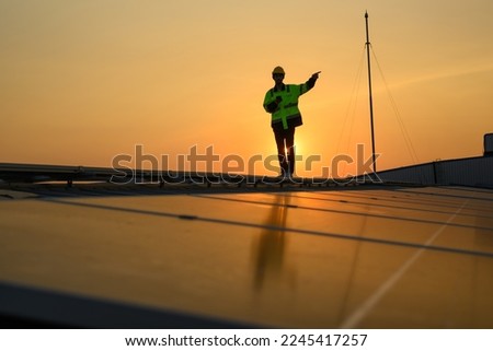 Silhouette of technician engineer checking and repairing solar panels on rooftop of solar cell farm power plant, Renewable energy source for electricity and power