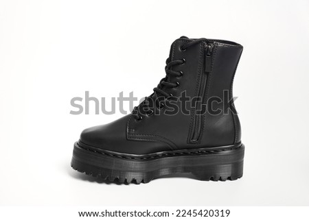 One black women combat boot on high heel platform with lug sole on isolated white background. Military stylish high heel platform combat shoe for woman leg, new footwear trend