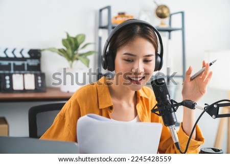 Young Asian woman use microphones wear headphones with laptop record podcast interview for radio. Content creator concept. Royalty-Free Stock Photo #2245428559