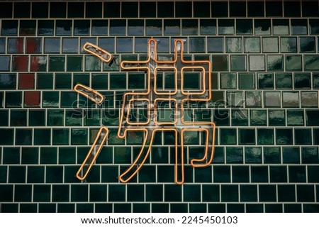 Neon sign in Chinese The word "boil" from neon on the background of a green brick wall.