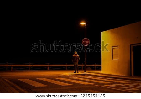 Adult man standing on road junction with stop sign at night. Cabo de Gata, Almeria, Spain