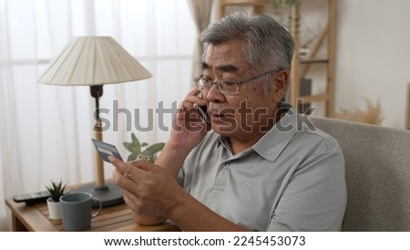 Sad old asian man with credit card call bank support by cellphone reporting about money fraud. senior male telling problem on smartphone while taking debit card. elderly grandpa talk on mobile phone
