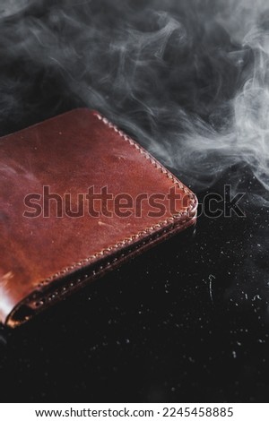 Stylish handmade brown leather wallet on a gray background. Product made of genuine leather.