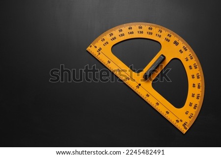 Yellow protractor on blackboard, top view. Space for text