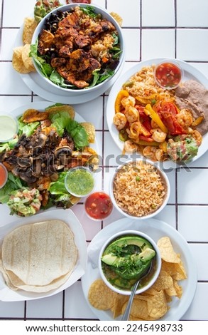 A top down view of several Tex-Mex entrees on a tile table surface.