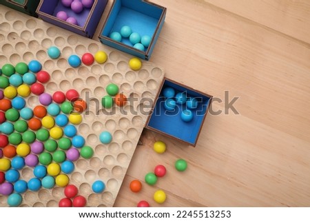 Wooden sorting board and boxes with colorful balls on table, flat lay. Montessori toy Royalty-Free Stock Photo #2245513253