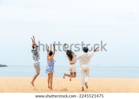 Group of Happy Asian people friends playing and jumping together on beach at seaside in sunny day. Man and woman enjoy and fun outdoor lifestyle travel at tropical island on summer holiday vacation. Royalty-Free Stock Photo #2245521475