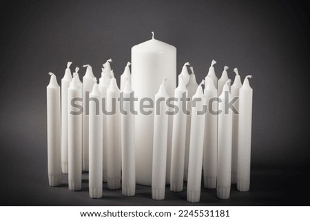 A group of white candles on a gray background. 