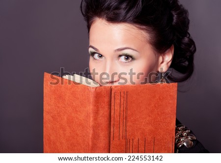 Attractive young woman holding book over black