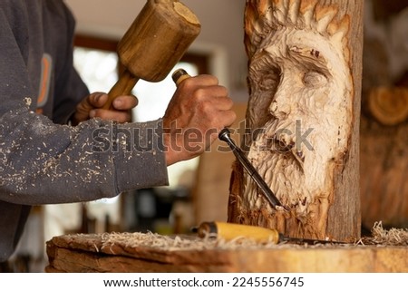 closeup of artisan wood worker sculpting carving a wood spirit face  Royalty-Free Stock Photo #2245556745
