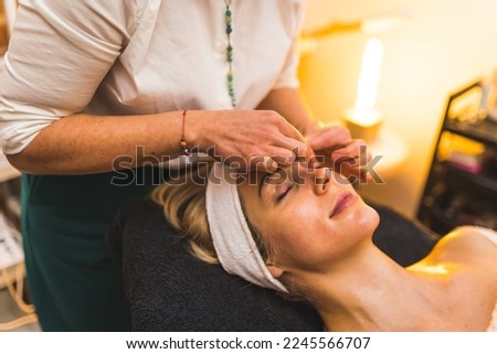 Beautician using her hands to do a face massage on her relaxed blonde female client. Close-up. High quality photo