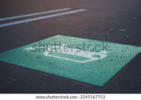symbolic graphic of a car with cable plug painted in green and white on parking lot. charging station. electro mobility concept. selective focus