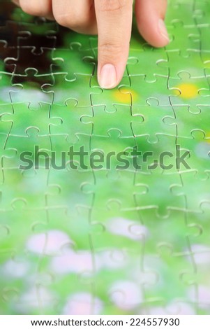 Hand holding puzzle piece on wooden table background
