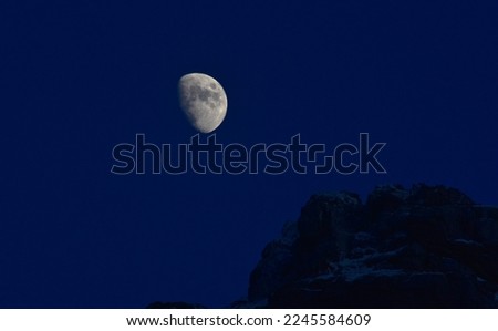the moon against the background of the evening sky over the top of the rock