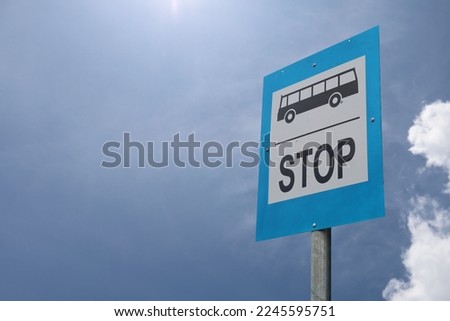Bus stop sign in the street against blue sky