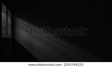 interior of dark room. shadow of the rays falling on the wall through the louvers. Light from the lamp and shadow on  room wall from roller window shutter. night club. black and white. Royalty-Free Stock Photo #2245596235