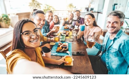 Multiracial group of friends having dinner party sitting at coffee bar table - Young people enjoying meal on morning brunch time - Life style concept with women and men at lunch break cafe bar Royalty-Free Stock Photo #2245609123