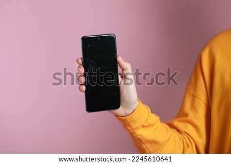 Woman showing damaged smartphone on pink background, closeup. Device repairing