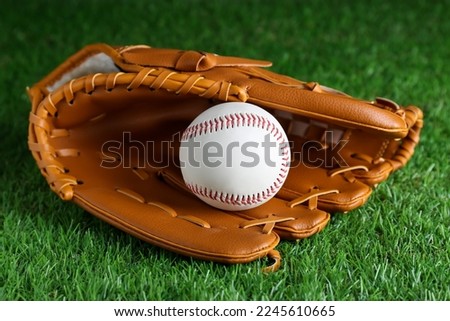Catcher's mitt and baseball ball on green grass. Sports game