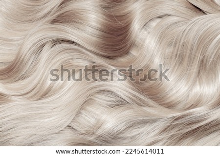 Blond hair close-up as a background. Women's long blonde hair. Beautifully styled wavy shiny curls. Hair coloring. Hairdressing procedures, extension. White hair Royalty-Free Stock Photo #2245614011