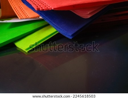 Bandung, Jan 05, 2023 : Bunch of colorful part nylon bags with shadows from black plastic film as background.
