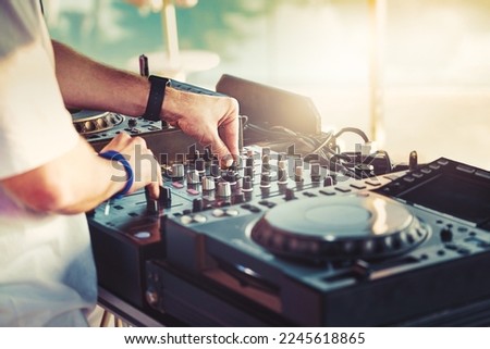DJ is mixing music with deejay controller at outdoor summer pool or beach party - nightlife people lifestyle concept Royalty-Free Stock Photo #2245618865