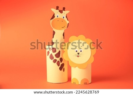 Toy giraffe and lion made from toilet paper hubs on orange background. Children's handmade ideas