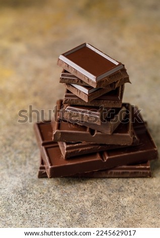 Broken chocolate pieces on dark background. Stack of dark chocolate. Chocolate concept