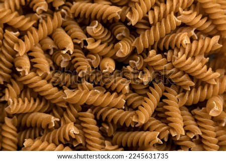 Dry whole grain or integral pasta background top view. Dry integral fusilli top view.  Royalty-Free Stock Photo #2245631735