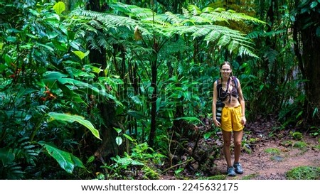 girl photographer stands under a large tree fern in the monteverde cloud forest in Costa Rica; hiking in the jungle in the tropical rainforest	