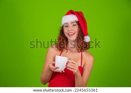 Pretty lady holding hot drink in hands with santa claus hat isolated green background