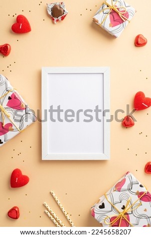 Valentine's Day concept. Top view vertical photo of photo frame gift boxes heart shaped chocolate candies straws candles and golden sequins on isolated pastel beige background with copyspace