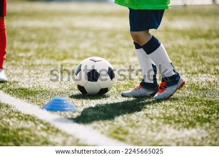 Little boy running and kicking classic soccer ball on training class