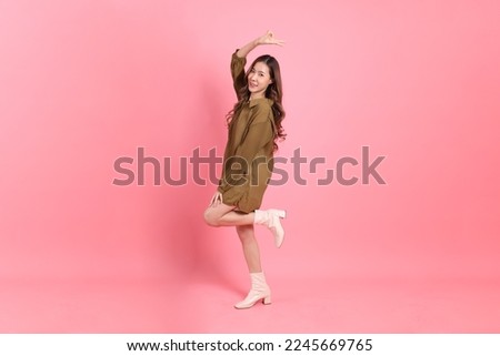 The young adult Asian woman with brown dressed standing on the pink background.