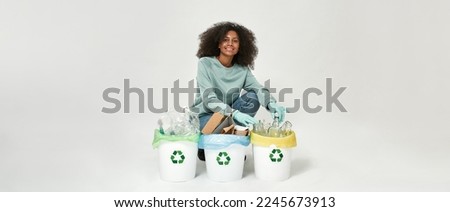 Smiling black girl sorting garbage in glass, plastic and cardboard bins and looking at camera. Waste disposal and recycling. Environmental sustainability. White background. Studio shoot. Copy space