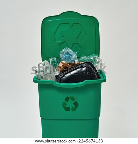 Front view of dustbin full of unsorted garbage. Ecology safety. Waste disposal and recycling. Environmental sustainability. Isolated on white background. Studio shoot Royalty-Free Stock Photo #2245674133