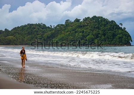 A beautiful girl in yellow shorts walks on a tropical beach with palm trees in manuel antonio national park in quepos, Costa Rica; tropical paradise beach in Costa Rica	
