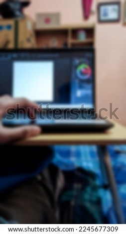 Blur photo of someone using a laptop to edit pictures