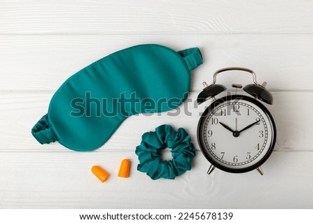Sleep mask, alarm clock, earplugs and sleeping pills on a white texture background.Top view.FLETLEY. The concept of restful and sound sleep. Insomnia. Royalty-Free Stock Photo #2245678139