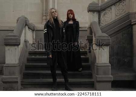 Young couple models standing on steps of  gothic cathedral  architectural building. A guy wearing long blond hair and girl with red hair
