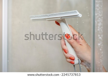 Shower cabin cleaning. Cleaning glass after using the shower. Cleaning glass with a rubber scraper. Royalty-Free Stock Photo #2245737813