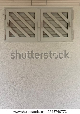 closed window with ventilation grilles in a white wall